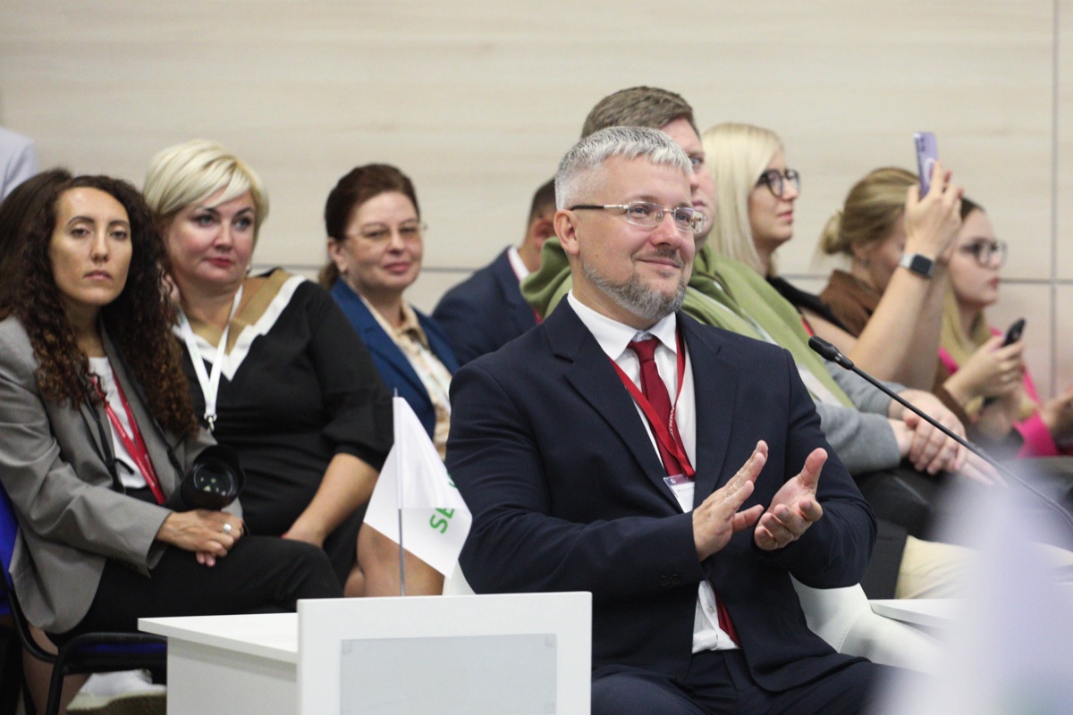 Участники аудитории аплодируют во время сессии делового мероприятия.