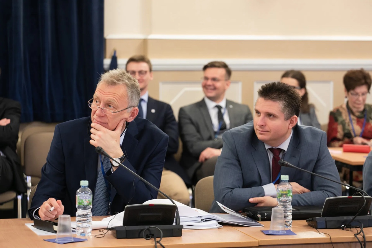 Делегаты сидят за конференционным столом с микрофонами во время формальной дискуссии.