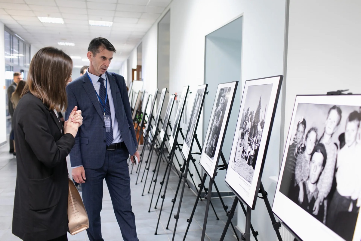 Гости рассматривают фотографии в рамках в выставочном коридоре.