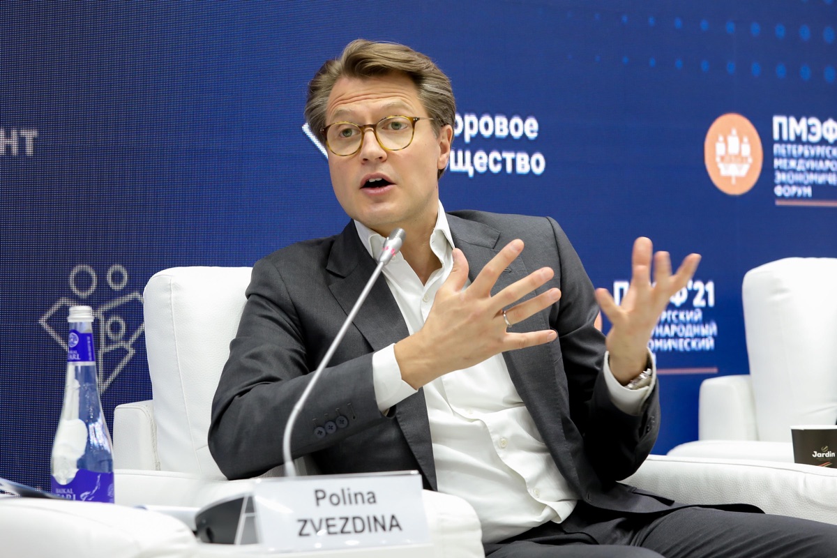 Деловой спикер жестикулирует у микрофона во время панельной дискуссии на форуме.