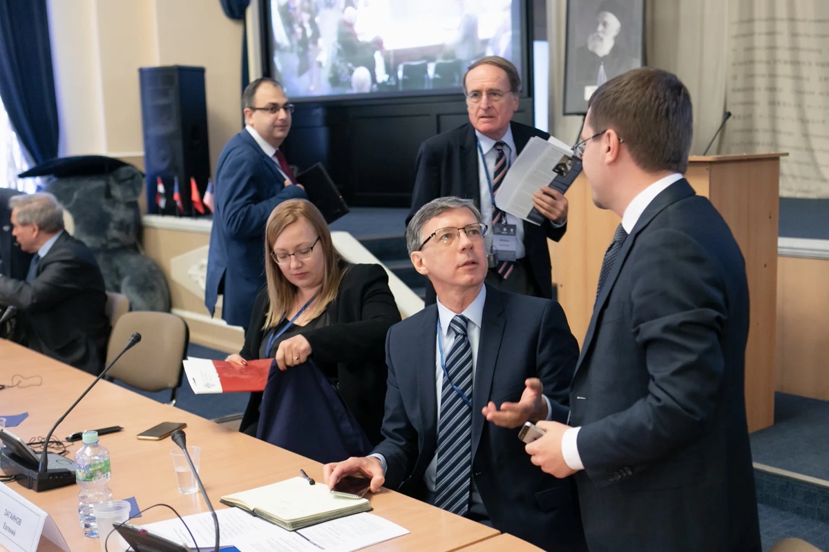 Делегаты разговаривают вокруг стола переговоров во время делового мероприятия.