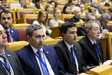 Делегаты сидят в зале во время конференционной сессии.